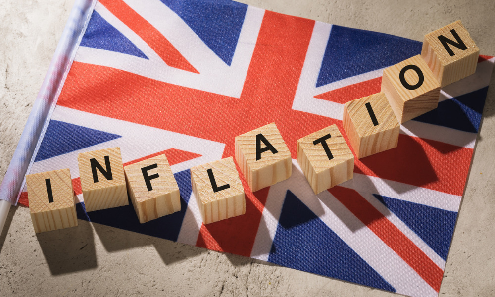 Blok kayu mengeja INFLATION menaik secara berperingkat di atas bendera Union Jack UK