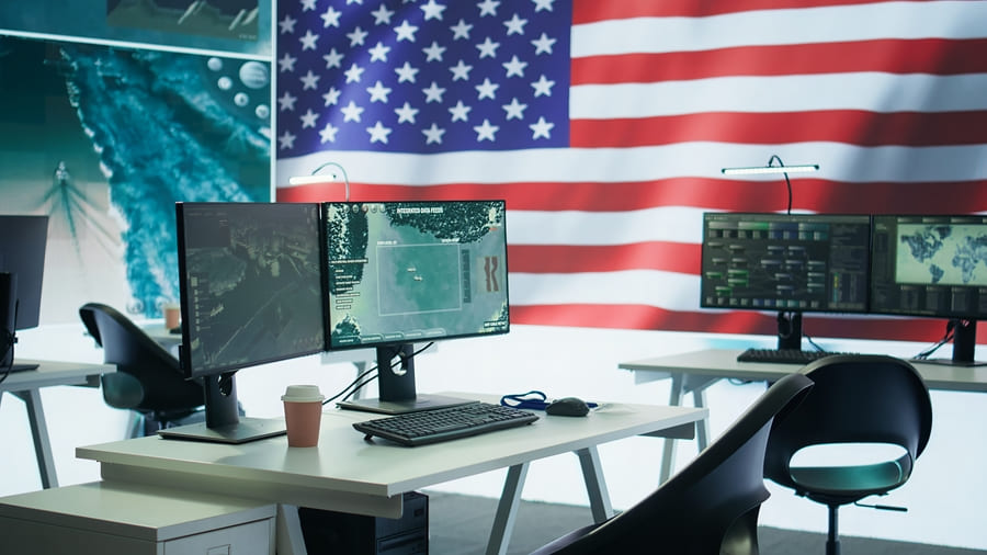 Trading desk with multiple monitors in front of a large US flag.